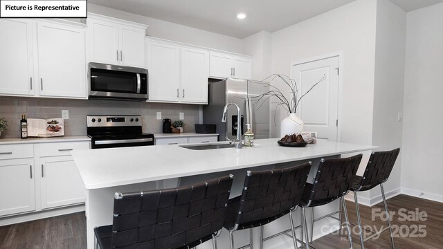 kitchen featuring a kitchen island with sink, appliances with stainless steel finishes, backsplash, and a sink