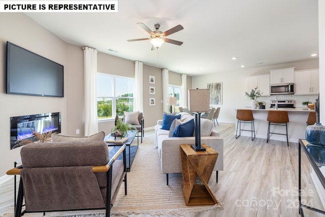 living room with ceiling fan, a fireplace, and light hardwood / wood-style flooring