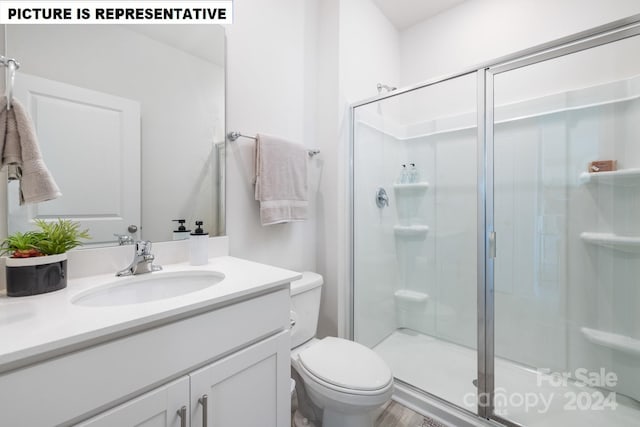 bathroom featuring wood-type flooring, vanity, toilet, and walk in shower