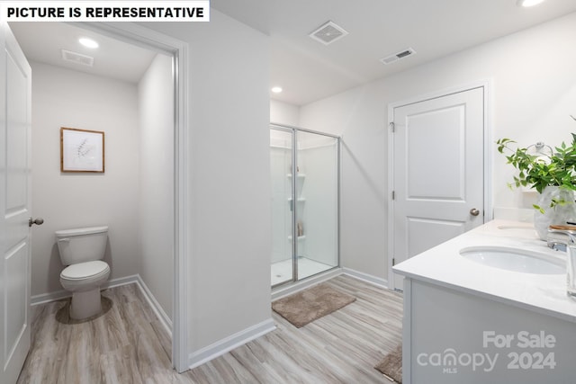 bathroom with an enclosed shower, vanity, toilet, and hardwood / wood-style flooring