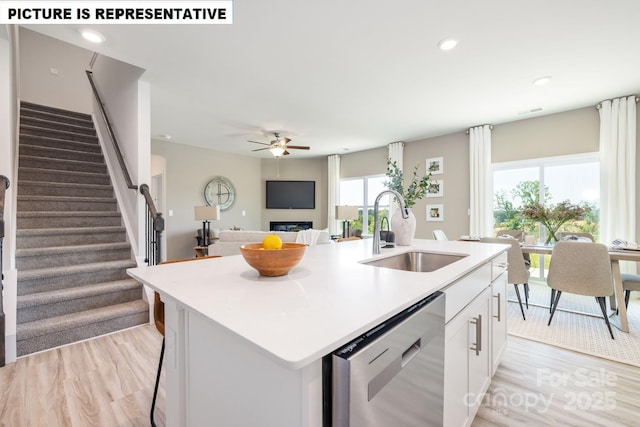 kitchen featuring a kitchen island with sink, a sink, light countertops, dishwasher, and light wood finished floors