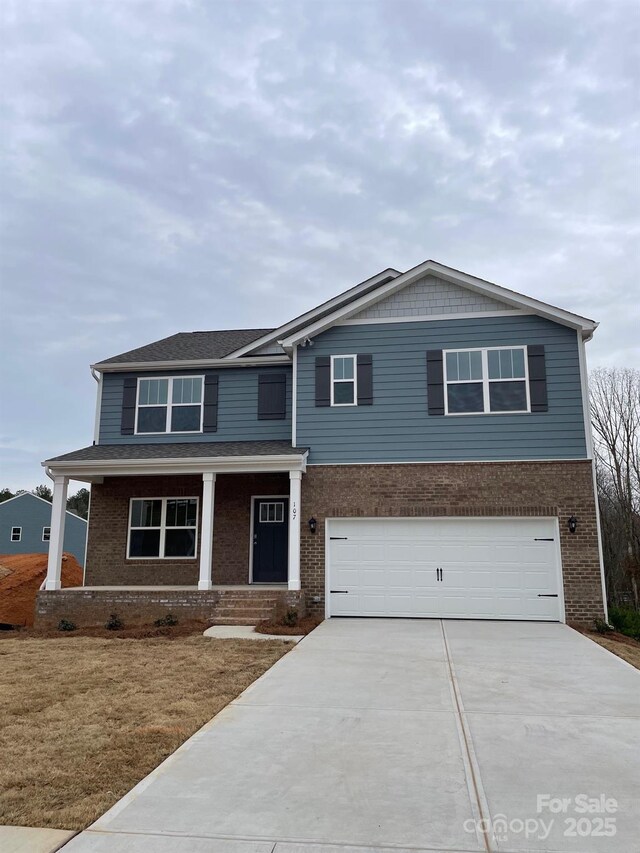 view of front facade with a porch, brick siding, driveway, and an attached garage