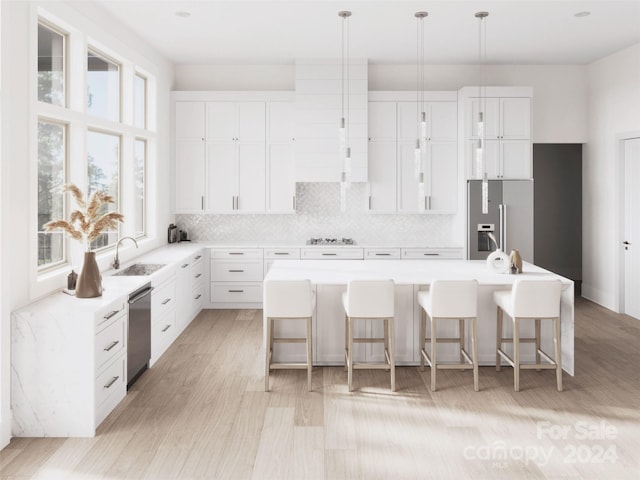 kitchen with appliances with stainless steel finishes, white cabinets, a kitchen island with sink, and a kitchen bar