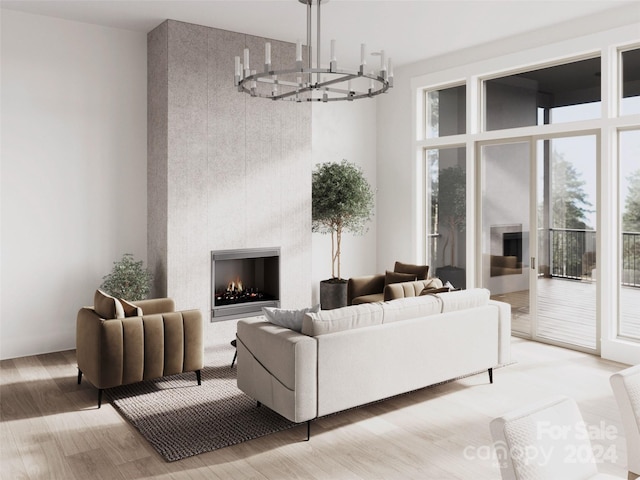 living room with an inviting chandelier, a fireplace, and light hardwood / wood-style flooring