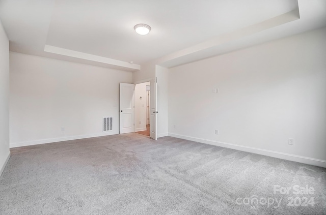 empty room with a tray ceiling and carpet flooring