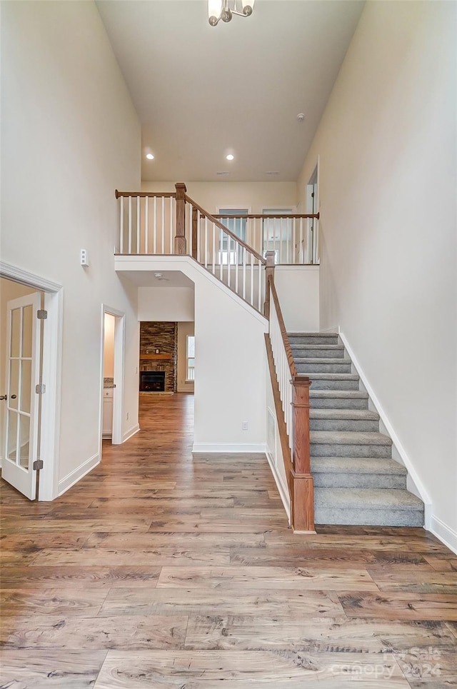 staircase with a towering ceiling and hardwood / wood-style flooring