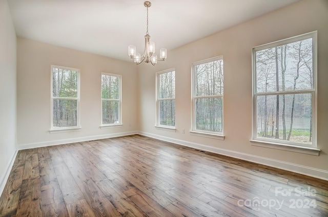 unfurnished dining area featuring hardwood / wood-style flooring and a notable chandelier