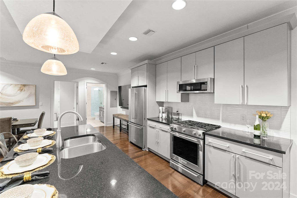 kitchen featuring tasteful backsplash, sink, decorative light fixtures, dark wood-type flooring, and high end appliances