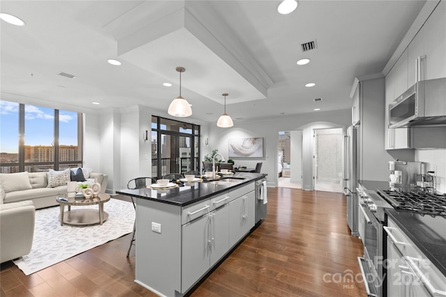 kitchen with sink, dark wood-type flooring, a kitchen bar, and gray cabinetry