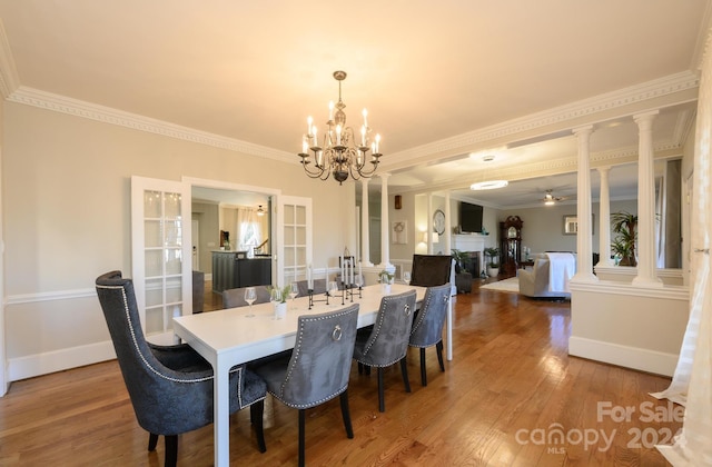 dining space with wood-type flooring, ornate columns, and ornamental molding