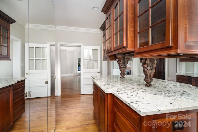 kitchen with light stone countertops, light hardwood / wood-style floors, ornamental molding, and decorative light fixtures