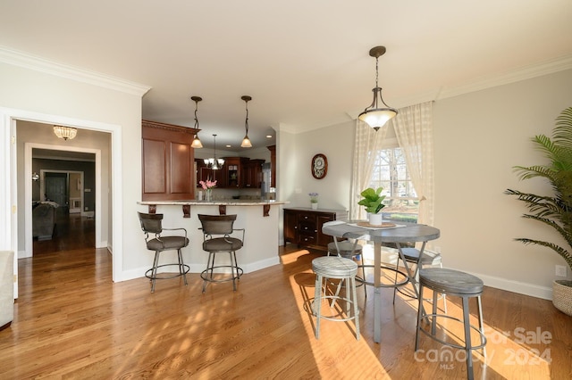 kitchen featuring pendant lighting, light hardwood / wood-style flooring, and ornamental molding