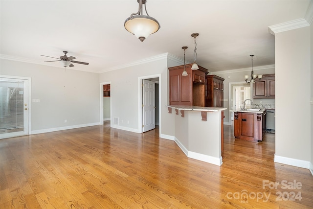 kitchen with light wood-type flooring, hanging light fixtures, ornamental molding, a kitchen breakfast bar, and ceiling fan with notable chandelier