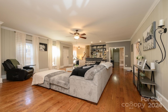 living room featuring ornamental molding, wood-type flooring, and ceiling fan