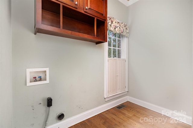 clothes washing area featuring washer hookup, wood-type flooring, crown molding, electric dryer hookup, and cabinets