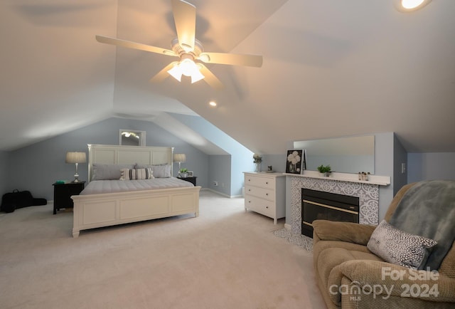 carpeted bedroom with vaulted ceiling, a tiled fireplace, and ceiling fan