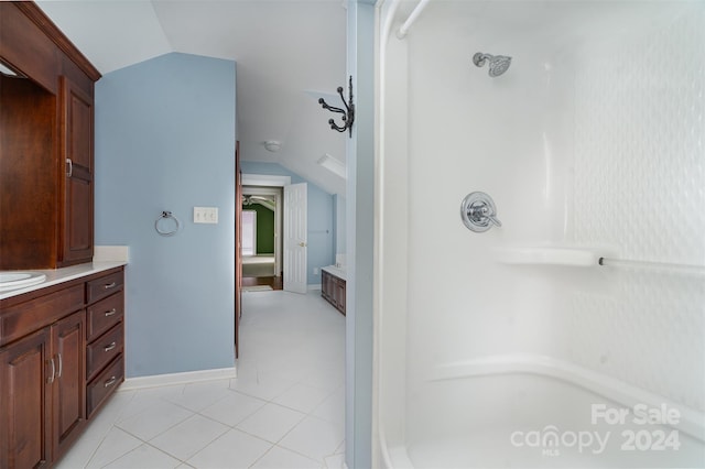 bathroom featuring walk in shower, vanity, lofted ceiling, and tile patterned flooring