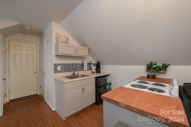 kitchen featuring black fridge, lofted ceiling, sink, white range, and light wood-type flooring