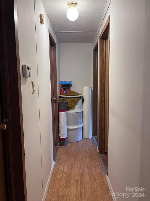 corridor with light hardwood / wood-style flooring and a textured ceiling