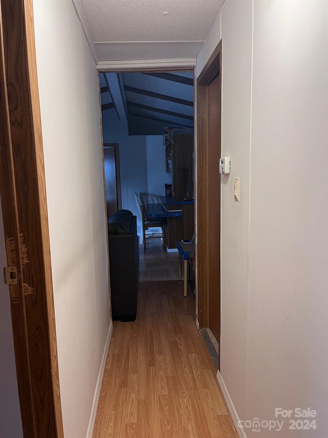 hallway featuring light hardwood / wood-style floors and vaulted ceiling