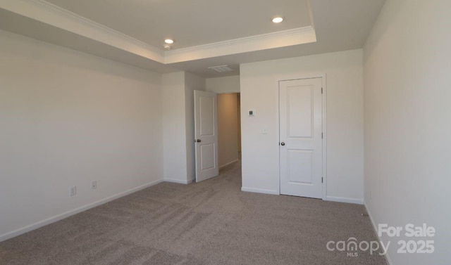 spare room featuring crown molding, light colored carpet, and a raised ceiling