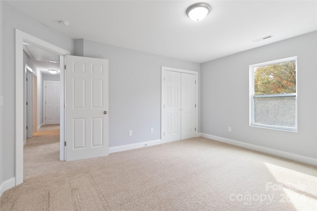 unfurnished bedroom with a closet and light colored carpet