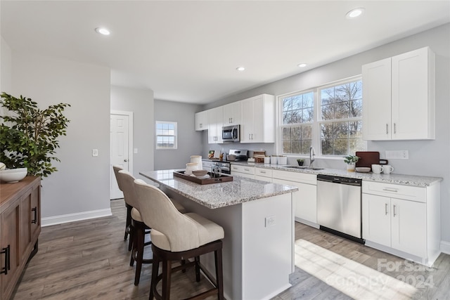 1038 Heath Helms Rd, Monroe, NC 28110 - kitchen featuring stainless steel appliances, wood finished floors, a kitchen bar, a kitchen island, and white cabinets
