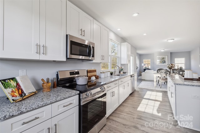 1038 Heath Helms Rd, Monroe, NC 28110 - kitchen featuring stainless steel appliances, light wood-style flooring, open floor plan, white cabinetry, and light stone counters