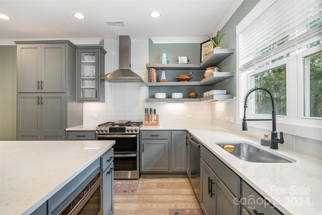 kitchen with light stone countertops, appliances with stainless steel finishes, tasteful backsplash, and wall chimney range hood