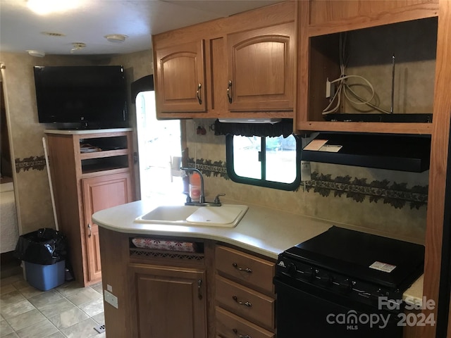 kitchen with light tile patterned floors, black range, backsplash, and sink