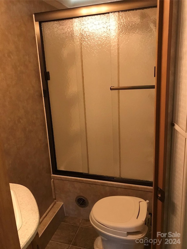 bathroom featuring toilet, an enclosed shower, and tile patterned floors