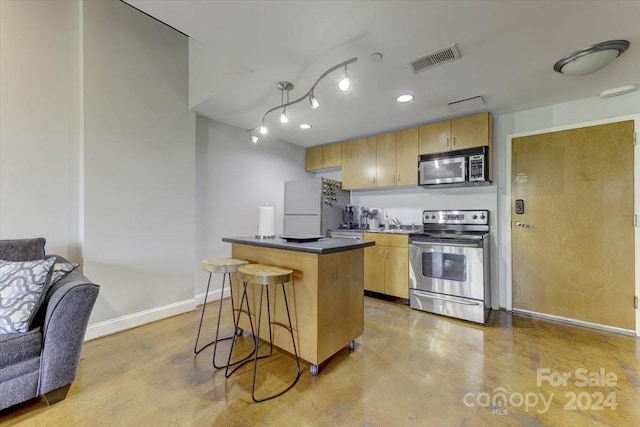 kitchen with light brown cabinets, a breakfast bar area, appliances with stainless steel finishes, and a center island