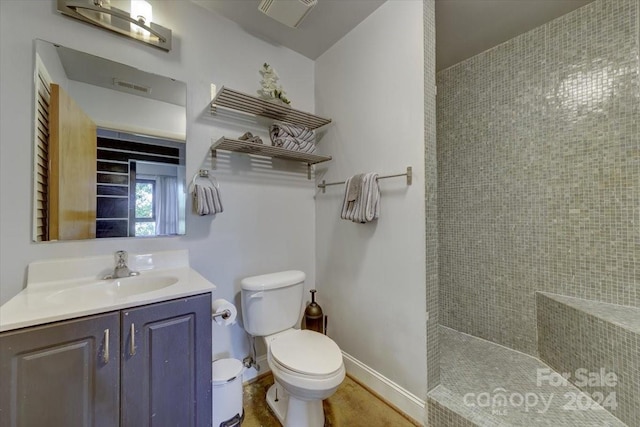 bathroom featuring a tile shower, vanity, and toilet