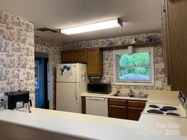 kitchen with a textured ceiling, sink, and white appliances