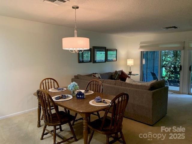 carpeted dining room featuring a textured ceiling