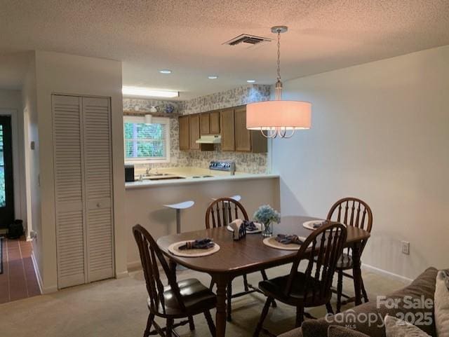 dining space featuring a textured ceiling and light colored carpet