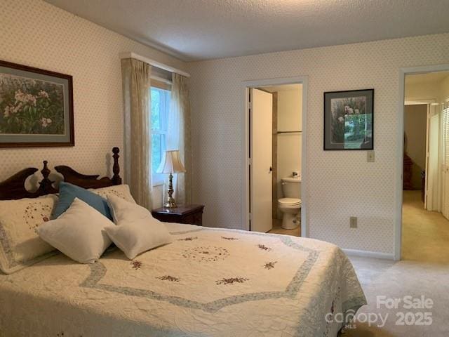 carpeted bedroom with a textured ceiling and ensuite bath