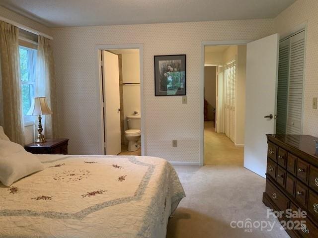 bedroom with light colored carpet, ensuite bathroom, and a closet