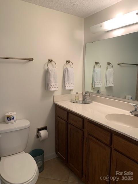 bathroom featuring toilet, vanity, tile patterned flooring, and a textured ceiling