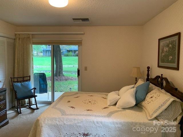 carpeted bedroom featuring a textured ceiling and access to exterior