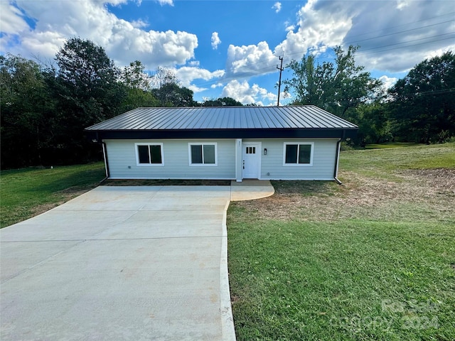 view of front facade featuring metal roof, a front yard, and concrete driveway