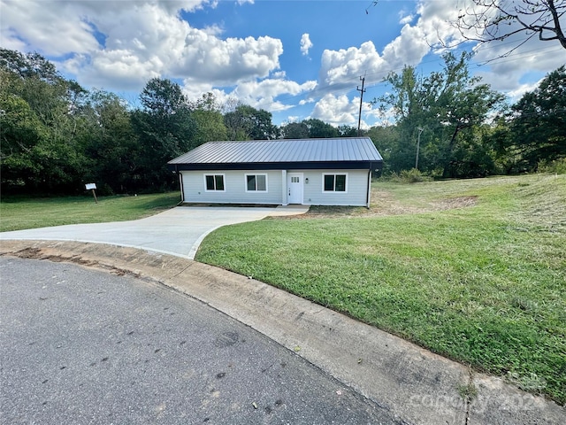 ranch-style home with metal roof, a front yard, and concrete driveway