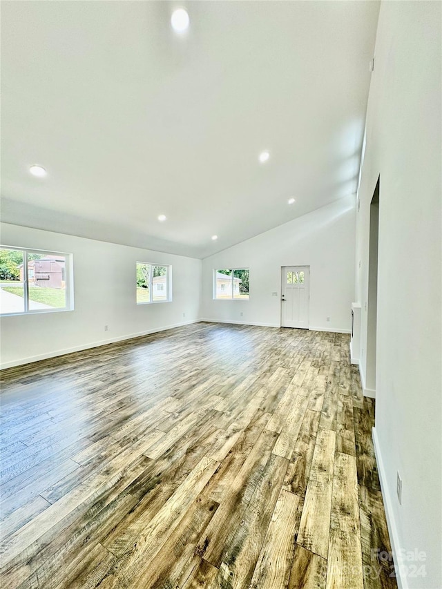 unfurnished living room featuring wood-type flooring, recessed lighting, baseboards, and vaulted ceiling