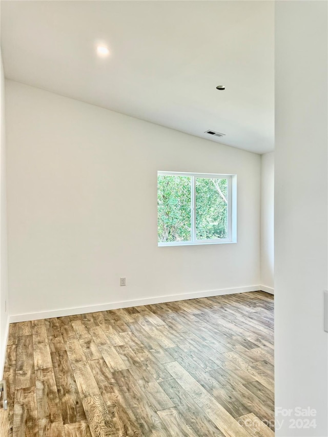 unfurnished room with baseboards, wood finished floors, and visible vents