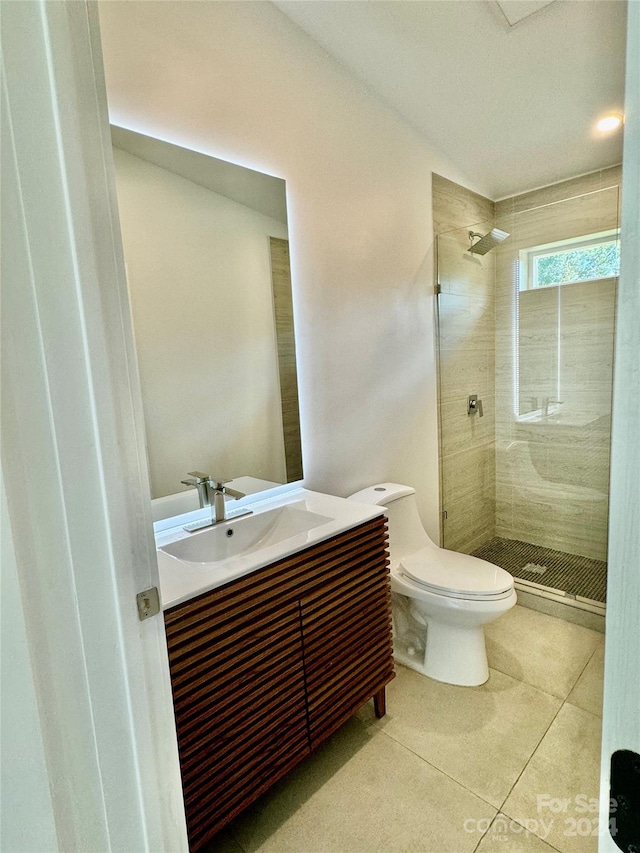 bathroom with tile patterned floors, tiled shower, vanity, and toilet