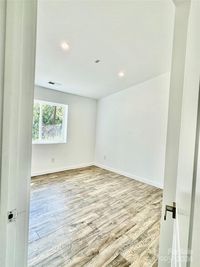 unfurnished room with baseboards, recessed lighting, wood finished floors, and visible vents