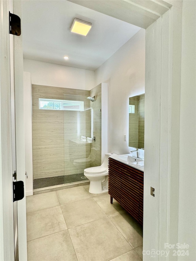 bathroom featuring tile patterned floors, tiled shower, vanity, and toilet