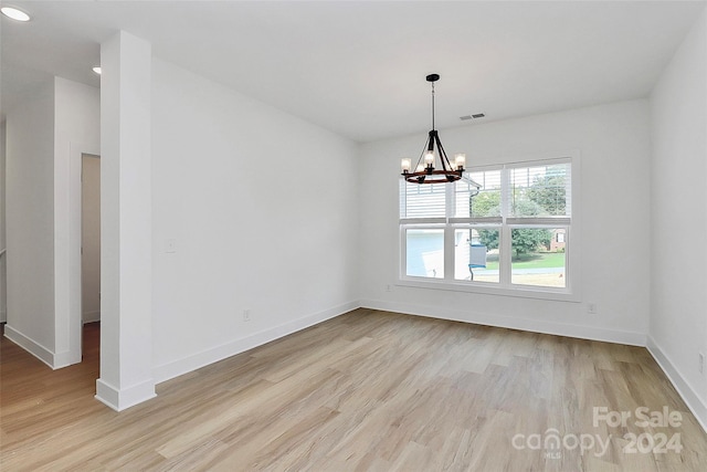 unfurnished dining area featuring light hardwood / wood-style floors and a chandelier