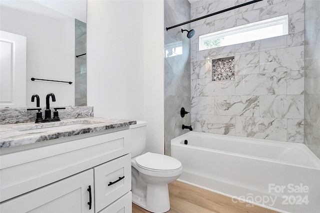 full bathroom featuring vanity, hardwood / wood-style floors, tiled shower / bath combo, and toilet