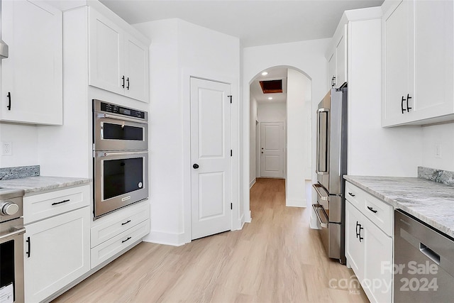 kitchen with white cabinets, light hardwood / wood-style floors, and light stone countertops